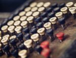 A close up on an old adding machine with white, black, and red buttons.